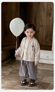 Détail d'une veste en coton pour bébé avec broderie chien et pantalon gris décontracté