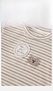 Detail of ribbed knit baby top featuring beige stripes and a cute 3D bear patch