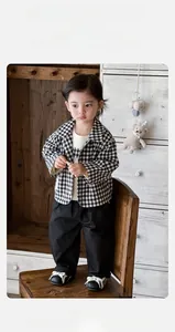 Detail of baby boy retro outfit with black and white grid shirt and casual trousers