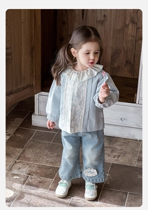 Dettaglio del colletto in pizzo floreale e fiori ricamati sui jeans blu per bambine