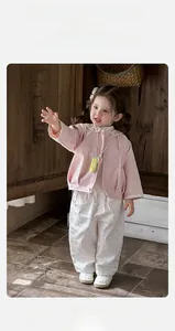 Détail de la veste rose pour bébé avec broderie en dentelle et pantalon à fleurs