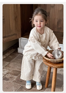 Dettaglio dei pantaloni a fiori per bambina con top a nido d'ape e pizzo stile rustico