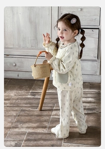 Detail of baby floral loungewear set with green leaf print and ruffled collar on wood background