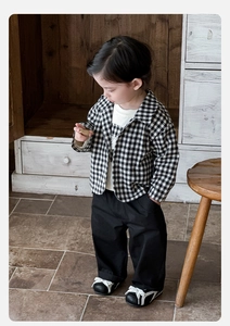 Detail view of baby boy three-piece outfit with black plaid shirt and loose pants
