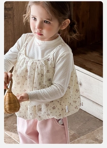 Close-up of floral ruffle vest and white long sleeve top with pink bow for toddler girls