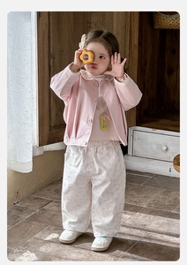 Détail de la veste rose pour bébé fille avec col en dentelle et pantalon à fleurs