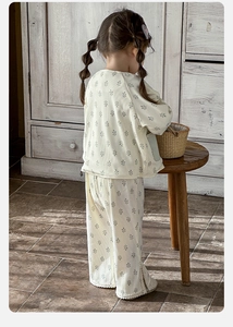 Detail view of cream toddler set showing floral leaf prints and lace hem on flared trousers
