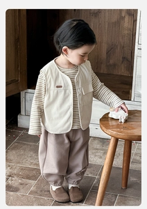 Detail view of boys beige corduroy vest, striped long-sleeve tee, and earthy harem pants