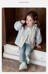 Dettaglio del set primaverile da bambina con colletto in pizzo e ricamo sui jeans blu