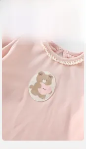 Dettaglio cardigan in maglia rosa per neonata con colletto in pizzo e ricamo