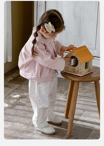 Détail du cardigan rose pour bébé avec col en dentelle et pantalon en coton fleuri