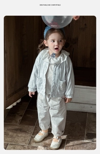 Detail of floral ruffle collar and blue striped texture on cotton toddler jacket