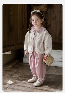 Detail of baby girl floral quilted jacket and pink trousers with lace and bow accents
