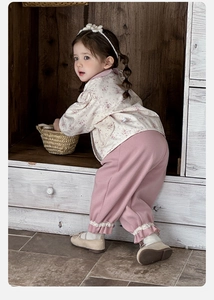 Detail of floral baby top with ruffle collar and pink pants in a rustic home setting