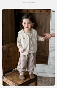 Three-piece boys corduroy vest set with striped shirt and trousers on wooden background