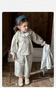 Detail of baby girl floral shirt and wide trousers set with knit headband for spring