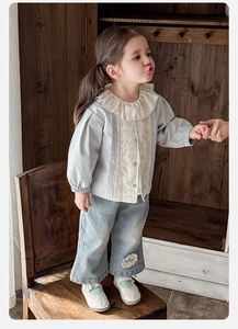 Dettaglio del colletto in pizzo e dei fiori ricamati sul set in denim per bambina