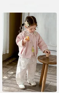 Détail du cardigan rose à col dentelle et pantalon floral avec accessoire pour bébé