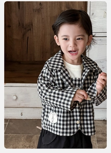 Detailed close-up of a baby boy's black and white checkered shirt with a cute bear patch