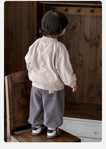 Vue arrière d'un enfant portant un sweat beige à manches longues et un jogging gris foncé