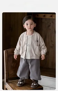 Détail du cardigan beige pour bébé avec imprimés cartoon et pantalon gris décontracté