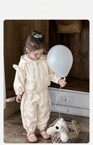 Dettaglio di una tuta beige per bambina con motivi a orsetto e giacca con cappuccio