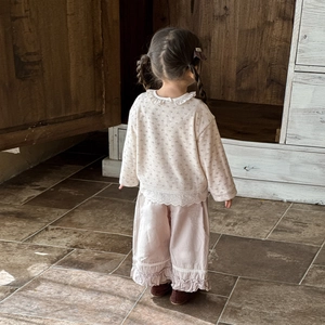 Pigiama floreale da bambina con pizzo e pantaloni larghi in una stanza in stile vintage