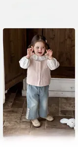 Détail du gilet rose avec broderie lapin et chemise blanche avec un jean à dentelle