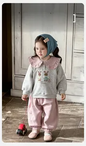 Détail d'un sweat-shirt pour petite fille avec col à volants et pantalon de jogging rose