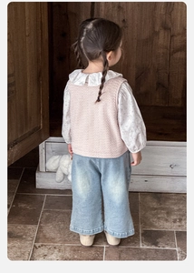 Vue arrière d'une chemise à col volanté, d'un gilet rose et d'un jean large bleu clair