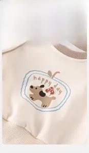Dettaglio del ricamo della felpa per neonati con cucciolo, fungo e scritta happy day