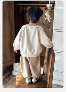 Vista posteriore del completo sportivo per bambini con felpa panna e pantaloni marroni