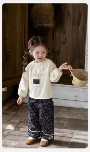 Dettaglio dei pantaloni floreali per bambina con pizzo e felpa color crema