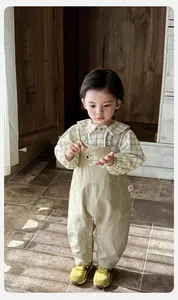 Détail d'une chemise à carreaux verte et d'une salopette avec écusson chien mignon