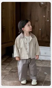 Detail of baby boy outdoor set featuring beige jacket, grey cargo pants, and printed T-shirt