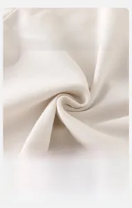 Macro view of soft cream-colored knitted cotton fabric showing ribbed texture and breathability