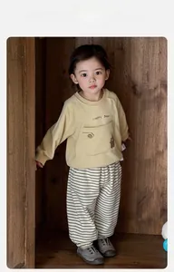 Dettaglio felpa gialla per bambini con ricamo orsetto e pantaloni a righe