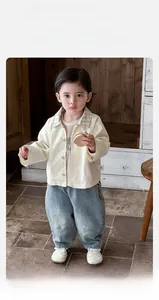 Détail de la veste en coton beige pour garçons et du jean rétro délavé large
