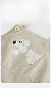 Détail de la salopette bébé avec broderie chiot et fermeture à bouton blanc