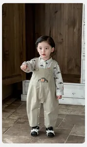 Detail of baby boy overall set with car print shirt and bear patch suspender pants