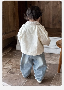 Détail d'un polo beige à manches longues et d'un jean décontracté pour petit garçon