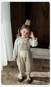 Detail von Blumenbluse mit Rüschenkragen und handgefertigtem Etikett an der Baby-Latzhose
