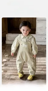 Détail de chemise à carreaux pour enfant et salopette beige avec patch brodé de chien mignon