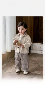 Detail of beige jacket and gray cargo pants outfit with cute cartoon embroidery