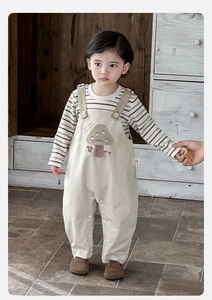 Détail de la salopette beige pour bébé avec broderie champignon et t-shirt à rayures