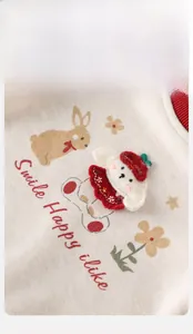 Detail of baby cotton knit romper featuring cartoon dog embroidery and red ribbed neckline