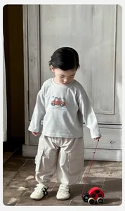 Detailed view of baby boy long-sleeve cotton T-shirt with red car print and beige cargo pants