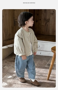 Détail du gilet beige pour bébé et du jean délavé bleu clair pour petit garçon