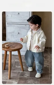 Détail de la veste beige pour bébé garçon avec col à carreaux et jean bleu denim