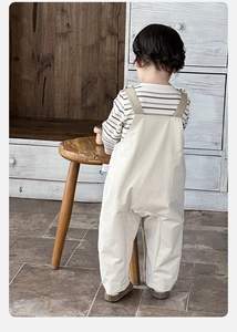 Détail du t-shirt rayé en coton et de la salopette marron pour bébé garçon en intérieur